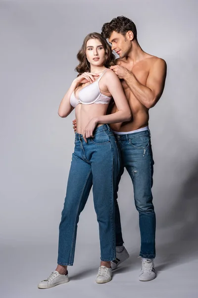 Shirtless man touching girlfriend in bra on grey — Stock Photo