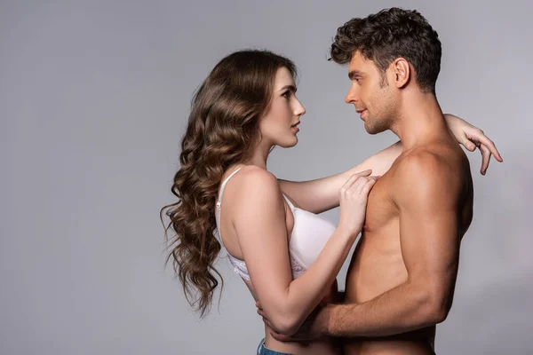 Vue latérale de la femme et de l'homme musclé se regardant sur le gris — Photo de stock