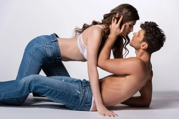 Profil de passionné et homme torse nu touchant les cheveux de petite amie en soutien-gorge sur blanc — Photo de stock
