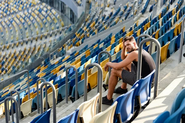 Jovem desportista sentado em escadas perto de assentos no estádio — Fotografia de Stock