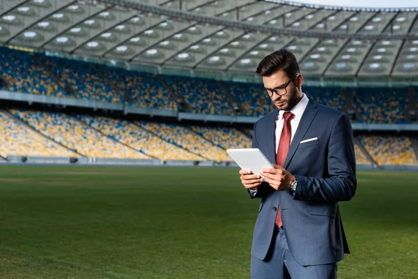 Jungunternehmer in Anzug und Brille mit digitalem Tablet im Stadion — Stockfoto