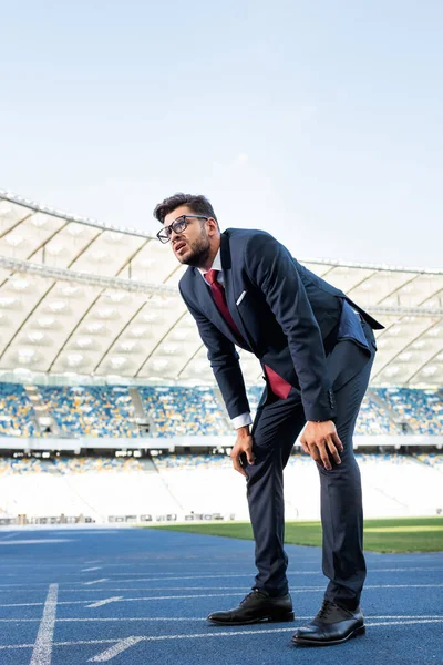 Joven hombre de negocios en traje de pie en pista de atletismo en el estadio — Stock Photo