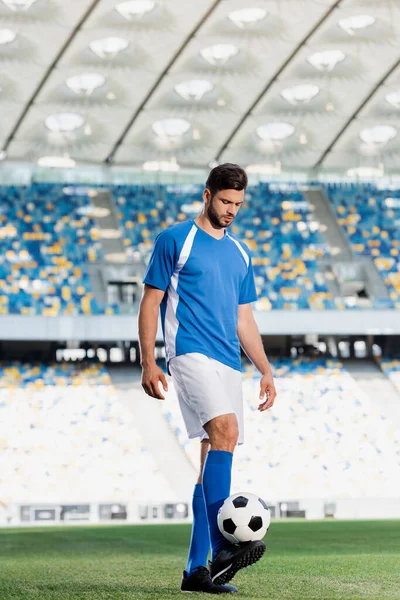 Fußballprofi in blau-weißer Uniform mit Ball auf dem Fußballplatz im Stadion — Stockfoto