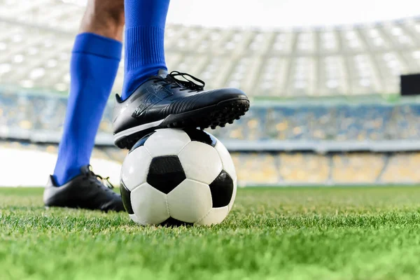Legs of professional soccer player in blue socks and soccer shoes on ball at stadium — Stock Photo