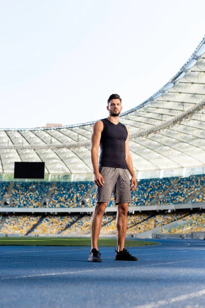 Handsome young sportsman on running track at stadium — Stock Photo