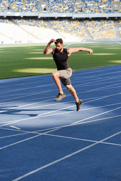 Schnelle gutaussehende Läuferin trainiert auf Laufstrecke im Stadion — Stockfoto