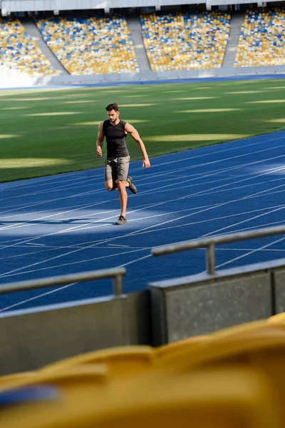 Messa a fuoco selettiva di corridore veloce bello esercizio sulla pista di corsa allo stadio — Foto stock