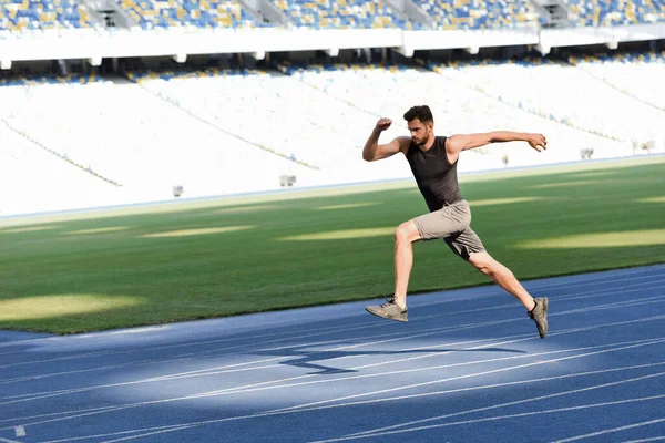 Rápido corredor guapo ejercicio en pista de atletismo en el estadio - foto de stock