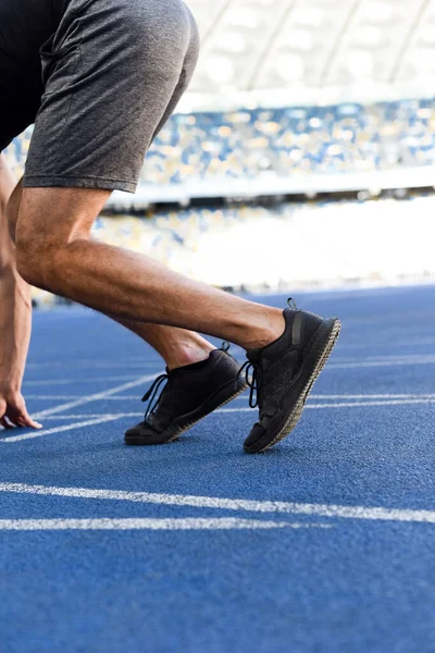 Cropped view of runner in start position on running track at stadium — Stock Photo