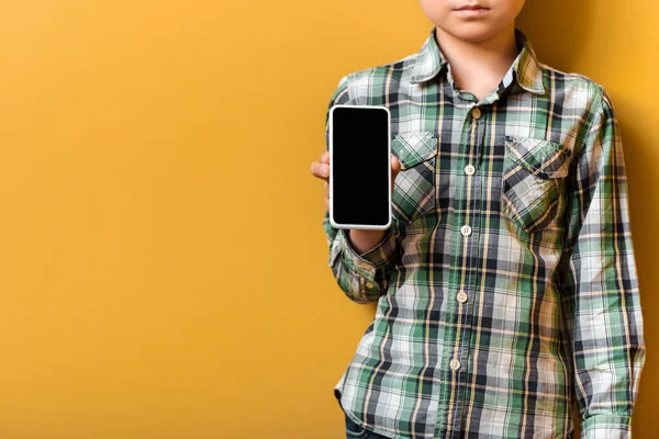 Vista panorámica del niño asiático que tiene teléfono inteligente con pantalla en blanco en amarillo. - foto de stock