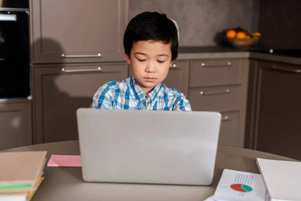 Chico asiático estudiando en línea con portátil en casa durante la cuarentena. - foto de stock