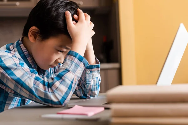 Печальный мальчик учится онлайн с ноутбуком дома во время карантина — стоковое фото
