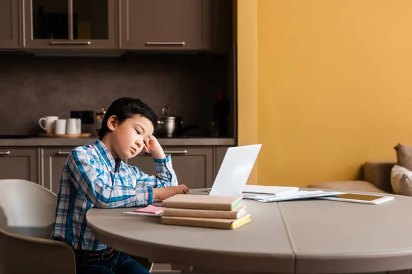 Asian boy studying online with books and laptop at home during quarantine — Stock Photo