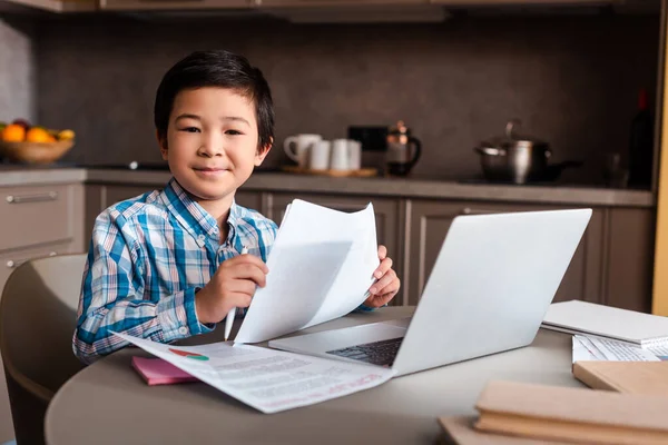 Sorridente asiático menino estudar online com laptop em casa durante auto isolamento — Fotografia de Stock
