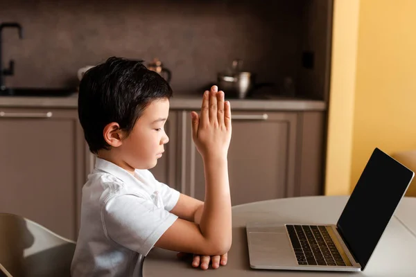 Chico asiático estudiando en línea en laptop con pantalla en blanco en casa durante la cuarentena. - foto de stock