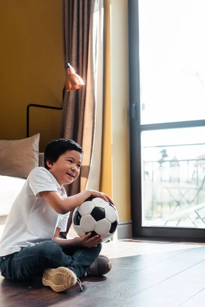 Happy asian boy with football ball watching sports match at home on quarantine — Stock Photo