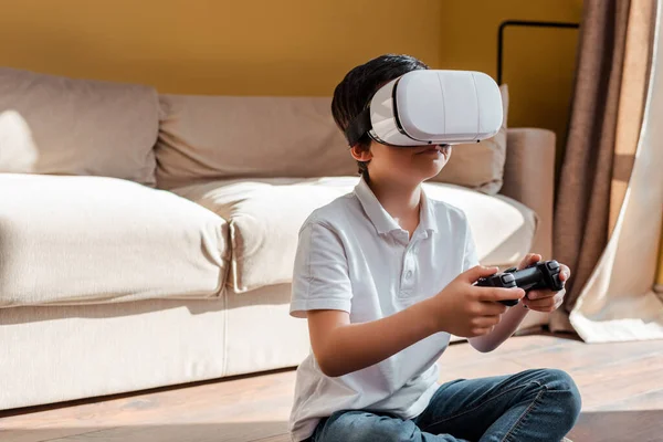 KIEV, UKRAINE - 22 AVRIL 2020 : un garçon joue à un jeu vidéo avec manette de jeu et casque de réalité virtuelle sur l'auto-isolement — Photo de stock