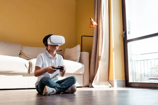 KYIV, UKRAINE - APRIL 22, 2020: kid playing video game with joystick and virtual reality headset on self isolation — Stock Photo