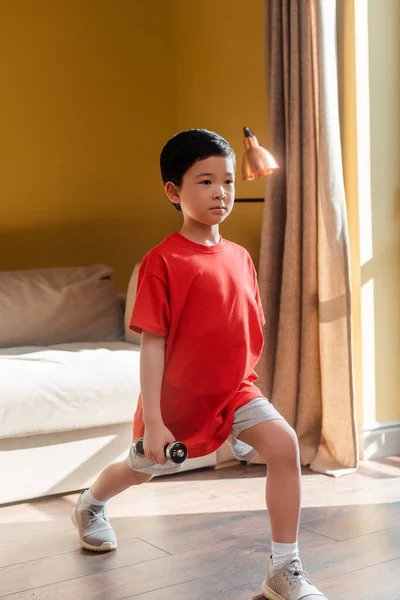 Sportivo asiatico ragazzo fare polmoni con manubri a casa durante auto isolamento — Foto stock