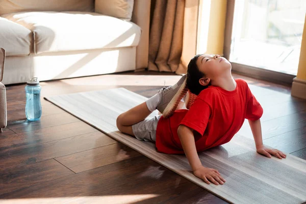 Ребенок растягивается на фитнес-коврике дома во время карантина — стоковое фото