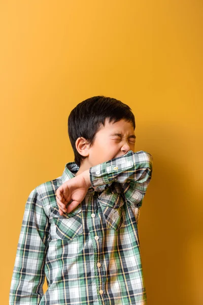Kranker asiatischer Junge niest während Selbstisolierung auf gelb — Stockfoto