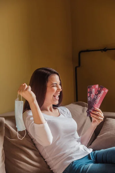 Excited woman holding night party tickets and medical mask, end of quarantine concept — Stock Photo