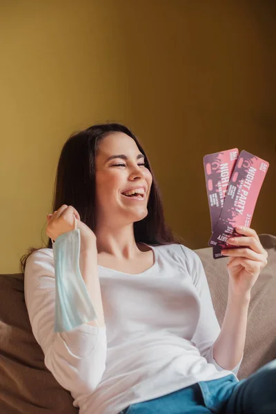 Happy woman holding night party tickets and medical mask, end of quarantine concept — Stock Photo
