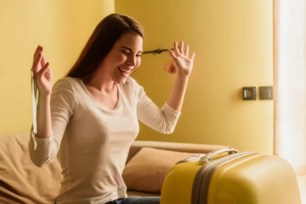 Jeune femme heureuse avec masque médical regardant les bagages, concept de fin de quarantaine — Photo de stock