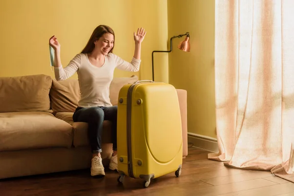 Joyeuse jeune femme avec masque médical regardant les bagages, concept de fin de quarantaine — Photo de stock