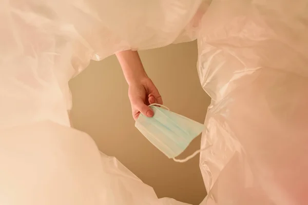 Vista recortada de la mujer arrojando máscara médica en el bote de basura, fin del concepto de cuarentena - foto de stock