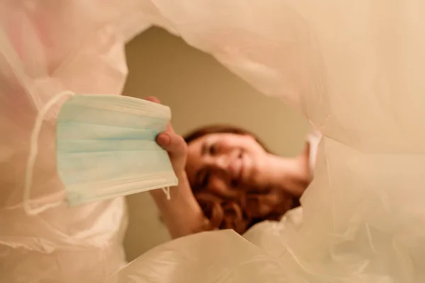 Vista inferior de la chica feliz lanzando máscara médica en el bote de basura, fin del concepto de cuarentena - foto de stock