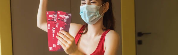 Horizontal image of happy woman in medical mask holding night party tickets — Stock Photo