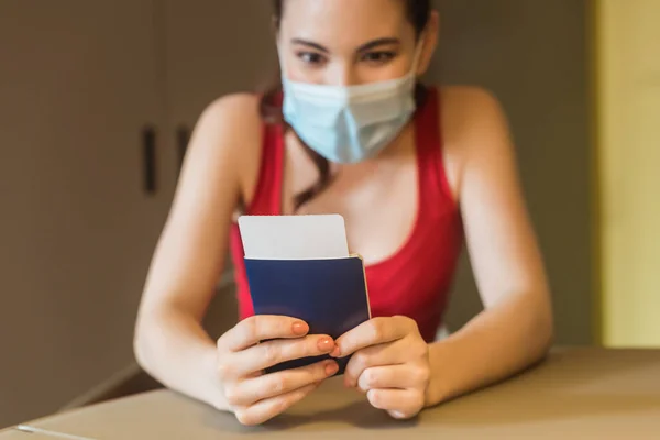 Enfoque selectivo de la mujer joven en máscara médica con pasaporte y billete de avión - foto de stock