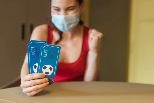 Enfoque selectivo de la mujer feliz en máscara médica celebración de entradas para partidos deportivos - foto de stock