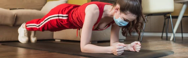 Orientamento panoramico della donna sportiva in maschera medica e abbigliamento sportivo esercizio sul tappeto fitness — Foto stock