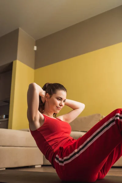 Mujer alegre en ropa deportiva haciendo ejercicio en la alfombra de fitness - foto de stock