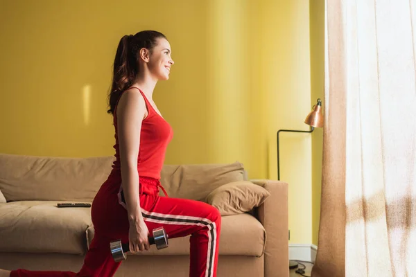 Side view of woman in sportswear working out with dumbbells — Stock Photo