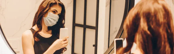 Panoramic crop of woman in black dress and medical mask taking photo in bathroom — Stock Photo