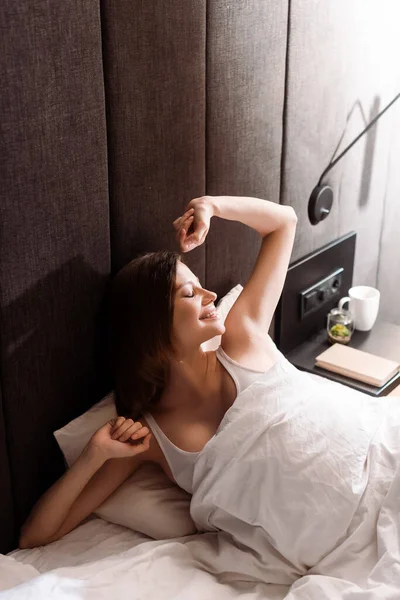 Fröhliche und schwangere Frau dehnt sich im Bett — Stockfoto