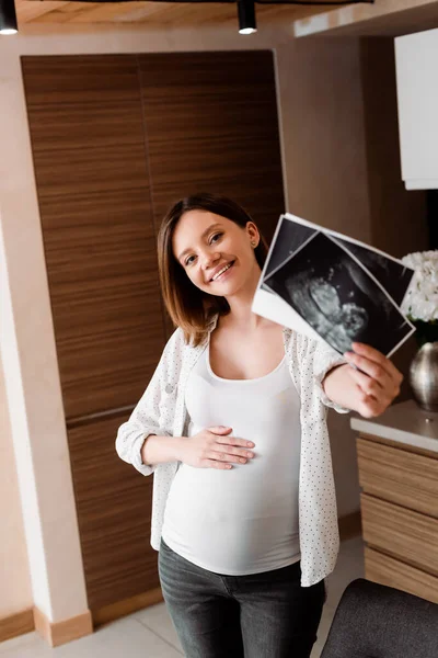 Foyer sélectif de femme heureuse et enceinte tenant des photos d'échographie — Photo de stock