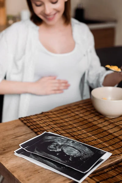Selective focus of ultrasound photos near happy and pregnant woman — Stock Photo