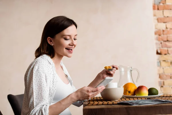 Happy and pregnant woman using smartphone near tasty breakfast — Stock Photo