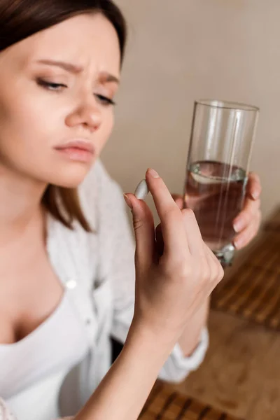 Selective focus of pregnant woman holding vitamins pill and glass of water — Stock Photo