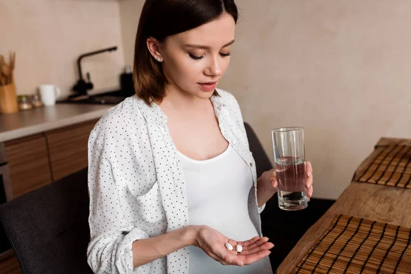 Pregnant woman holding vitamins pills and glass of water — Stock Photo