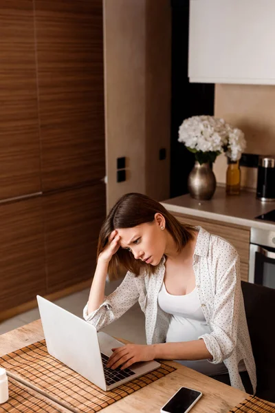 Freelancer cansado e grávida usando laptop em casa — Fotografia de Stock