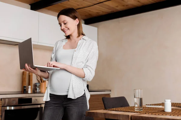Schwangere und glückliche Freiberuflerin mit Laptop zu Hause — Stockfoto