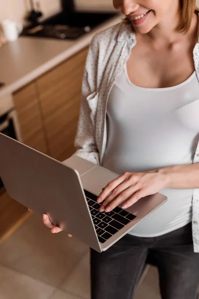 Vista ritagliata di freelance felice e incinta utilizzando il computer portatile — Foto stock