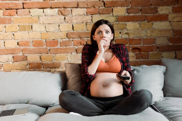 Effrayée et enceinte femme tenant télécommande et regarder le film — Photo de stock