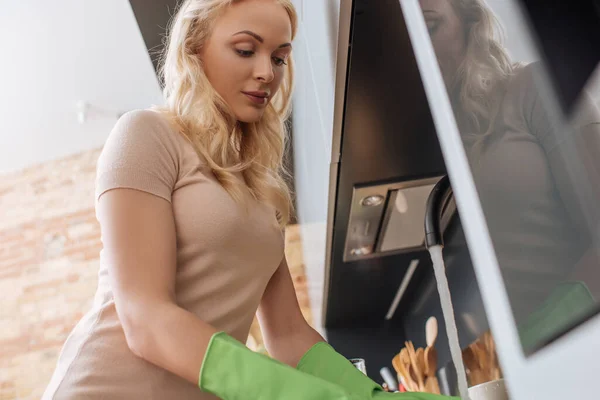 Low angle view of young housewife washing dishes in kitchen — Stock Photo