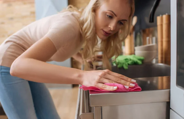 Selektiver Fokus der jungen Hausfrau Reinigung der Oberfläche von Küchenmöbeln mit Lappen — Stockfoto